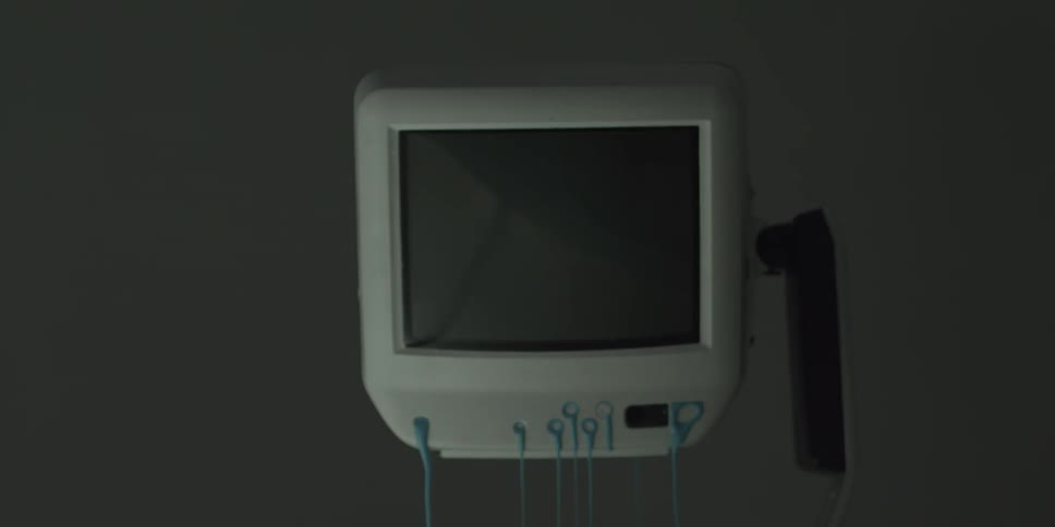 Blue liquid oozes from the knobs and cracks of a monitor in a lab