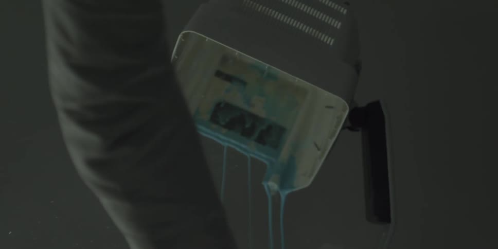 A man hits a screen bleeding blue liquid with a hammer
