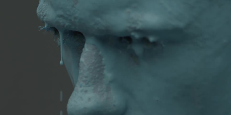 A man sits with blue liquid dripping over his brow and face