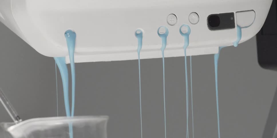A thick blue liquid is pouring out of a small electronic device