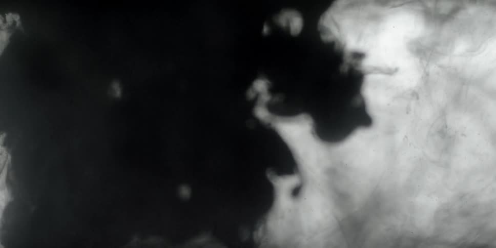 Black liquid is poured into a clear liquid and spreads out