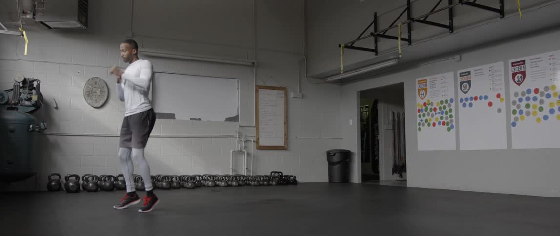 A man is jumping and stretching in a gym