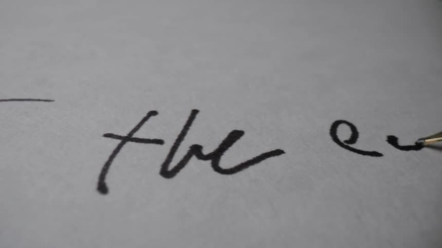 Tip of a pen writing the end on the paper sheet
