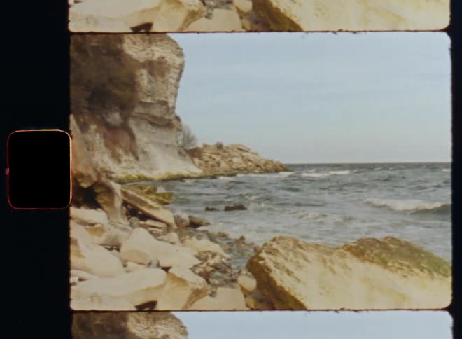 Ocean waves wash into a rocky coastline below a cliff during the day