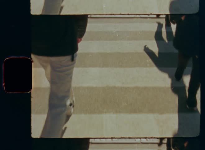 People are shown from waist to feet walking across a crosswalk
