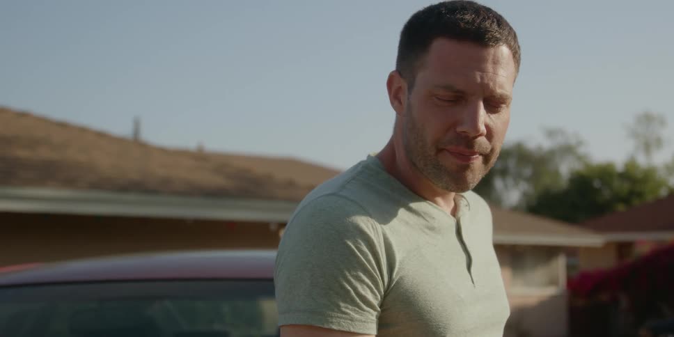 Man stands outdoors in residential neighborhood smoking while conversing
