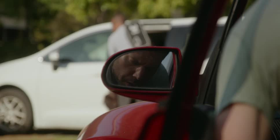 A man gets out of his car and waves at someone