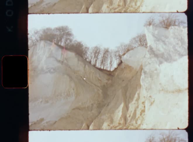 Film footage of a cliff with trees at the top