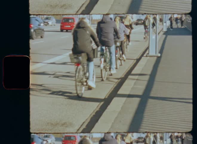 A group of cyclists travel along a bike lane beside a road during the day