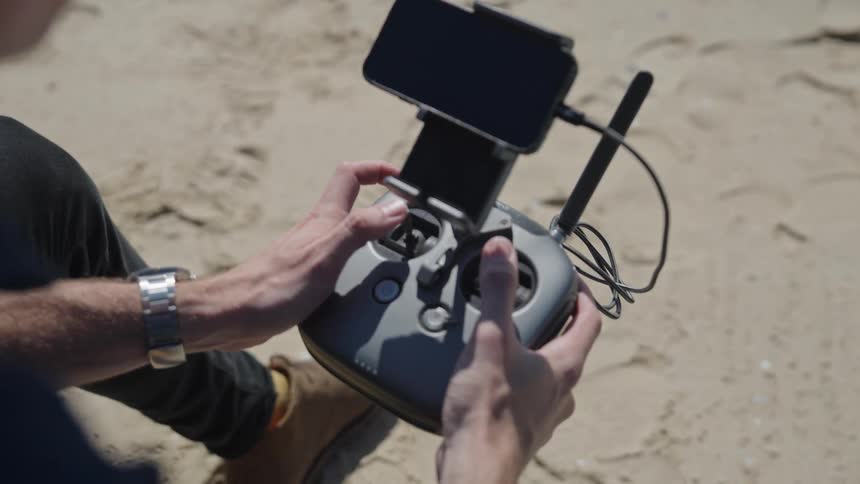 Man sits outdoors manipulating drone remote