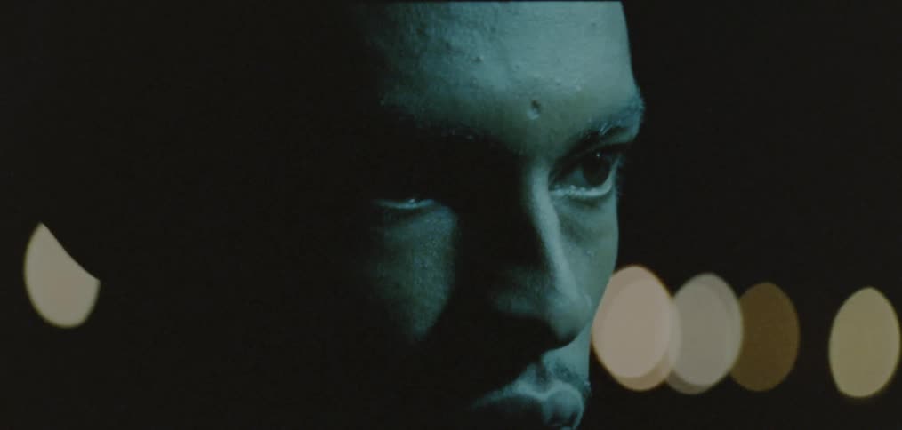 Light shines onto face of man as he focuses in dark area strewn with colored light spots
