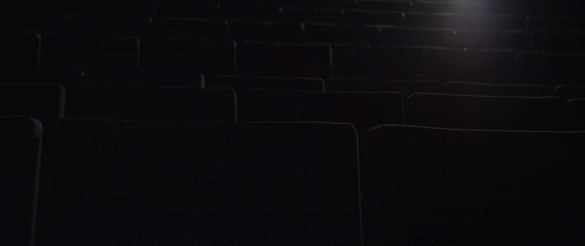 A light shines on seating in a dark theater