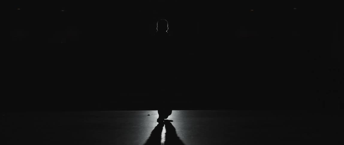 Light outlines silhouette of walking person and casts shadow onto floor