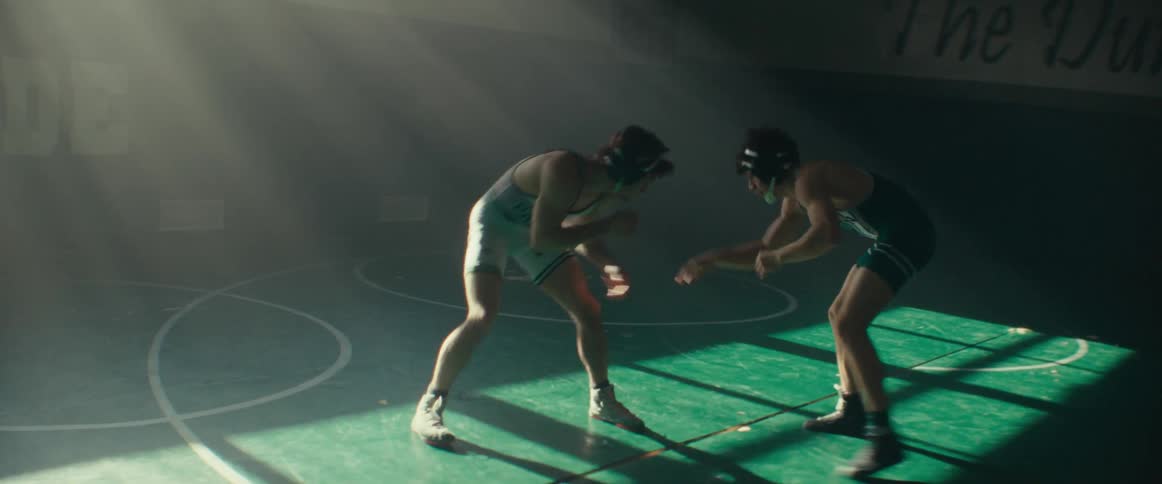 Two boys wearing wrestling uniforms in the school gym practice their moves