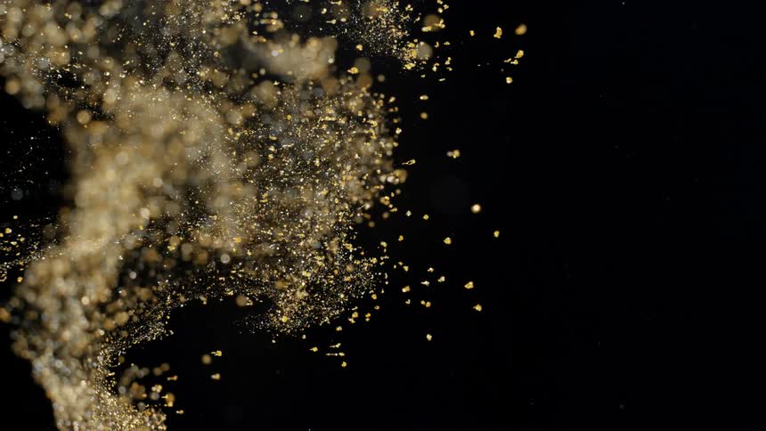 Mass of golden particles fly through darkness