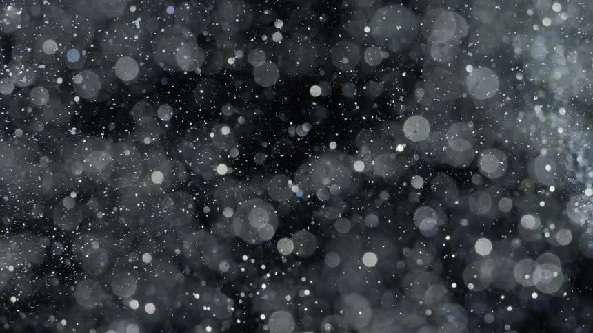 Crystalline particles create light spots as they swirl over black background
