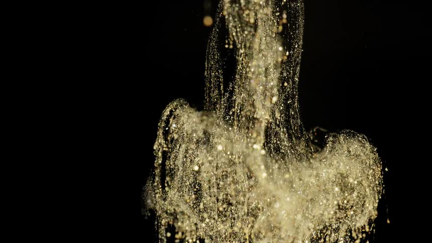 the golden liquid falls down on a black background