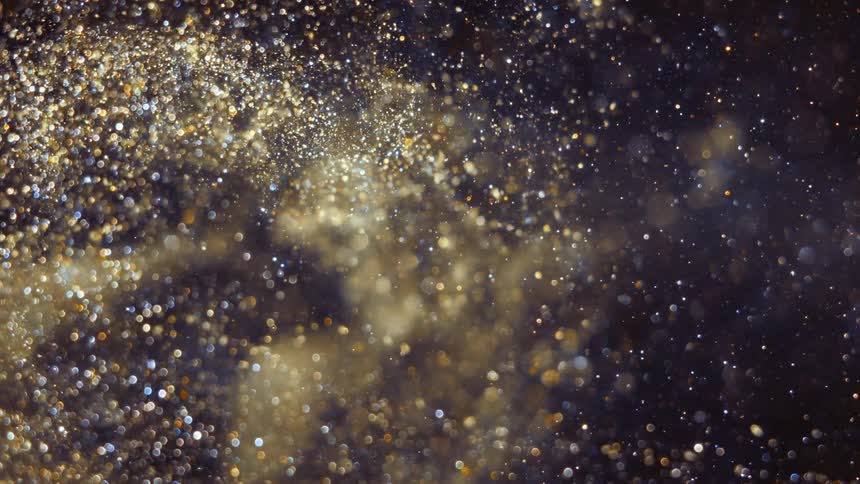 Golden crystalline particles swirl and glint against dark background