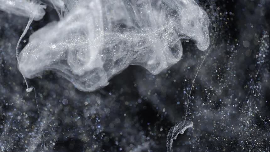 Crystalline vapor spreads and floats down against a sparkling black background