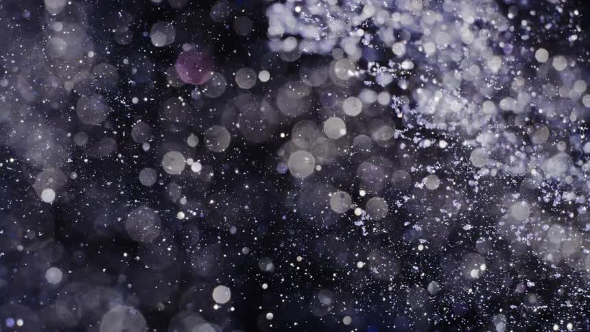 Sparkling chards fly through darkness creating pale spots of light