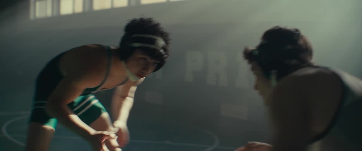 Young men wearing wrestling clothes practicing wrestling in the middle of an empty gym during the day