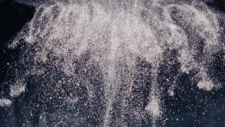 Cloud of glinting white glitter contrasts with black background