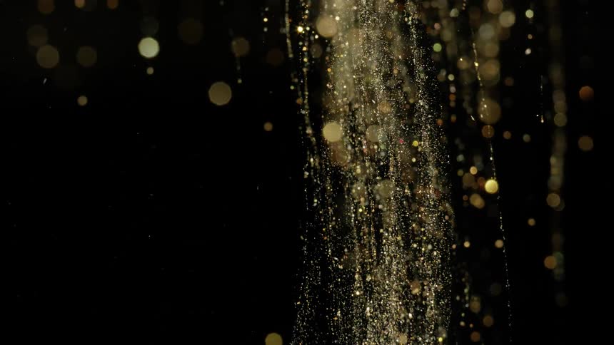 Golden particles fall in a stream against a black background