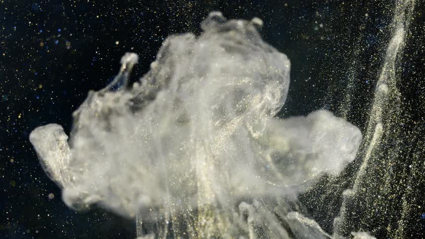 A glitter bomb explodes against a black background