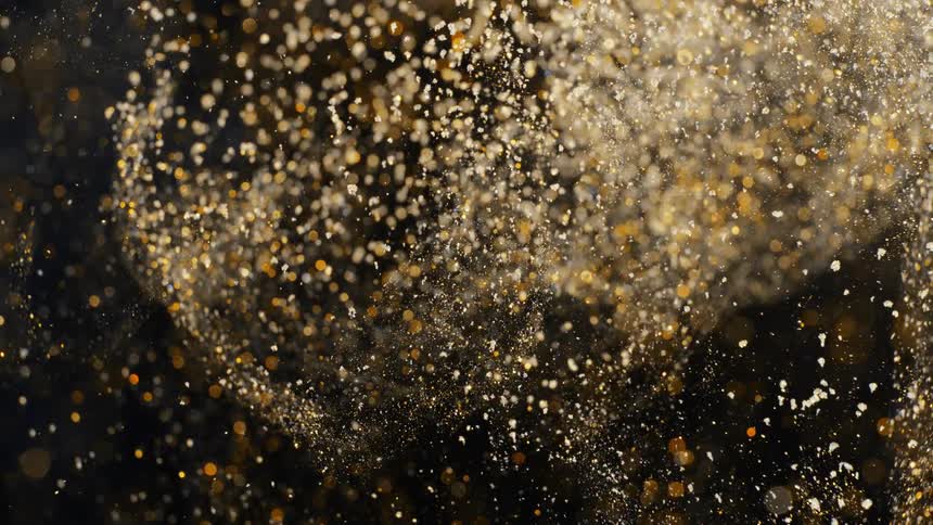 Golden particles fly through black background with light spots