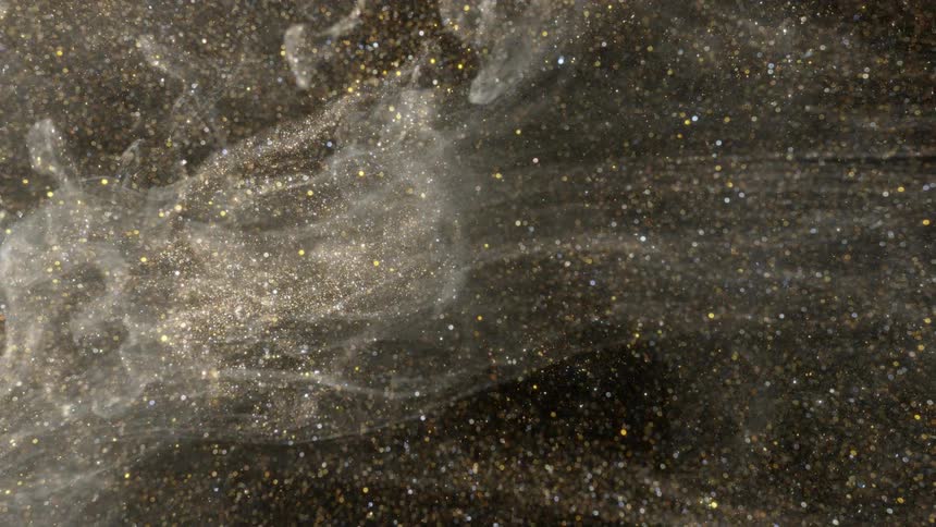 Pale cloud of particles floats through golden glitter background