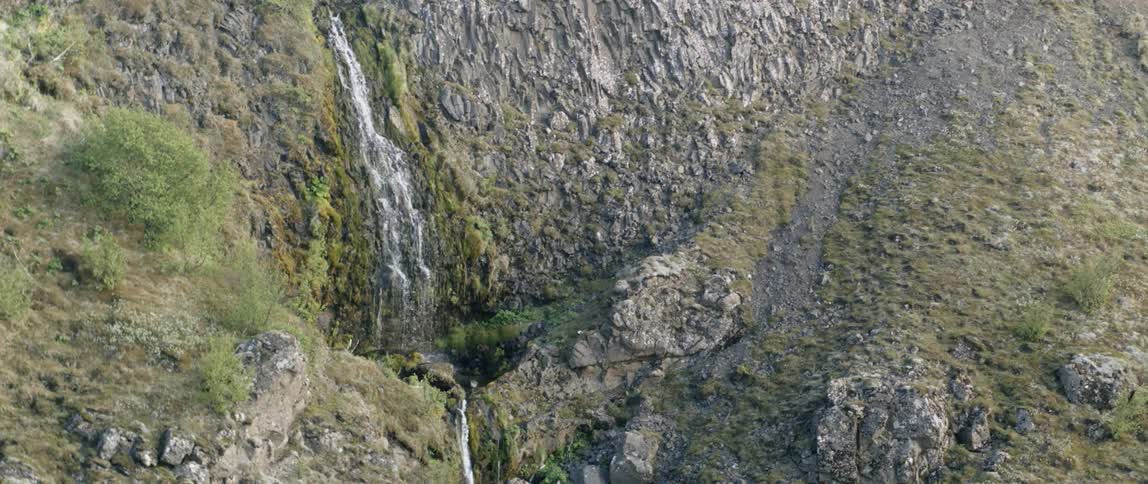A waterfall flows over a cliff in the wilderness