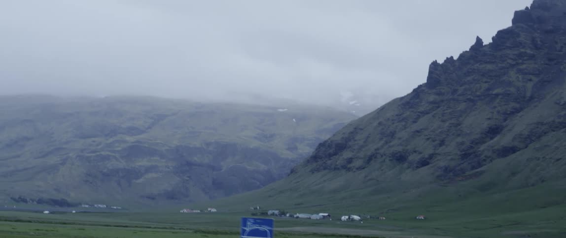 A car drives through a foggy rural area