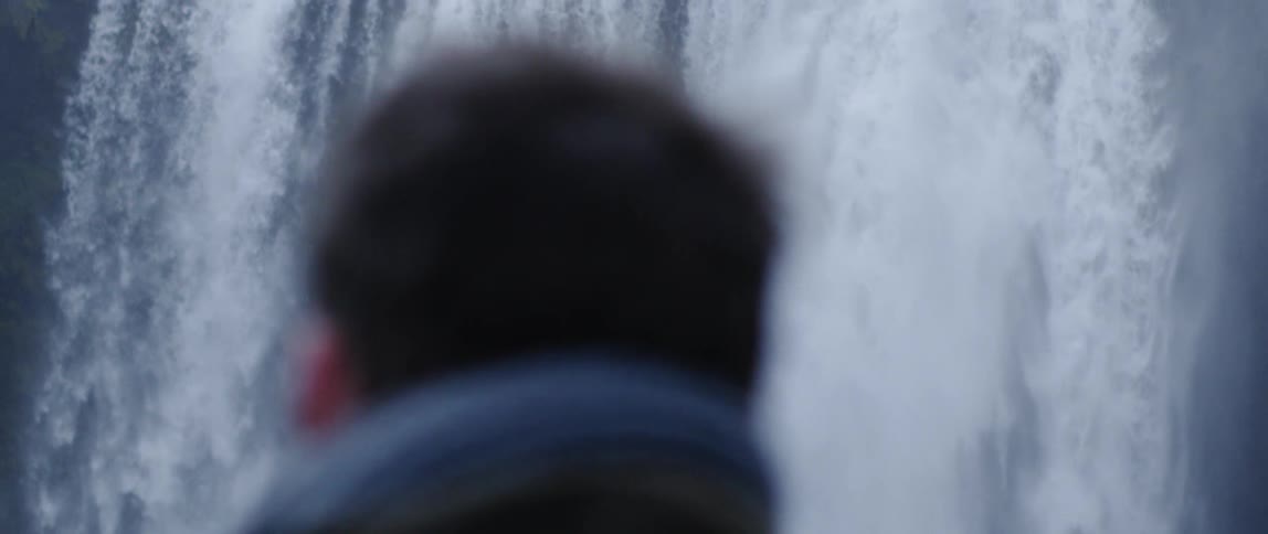 A man looks at a large waterfall