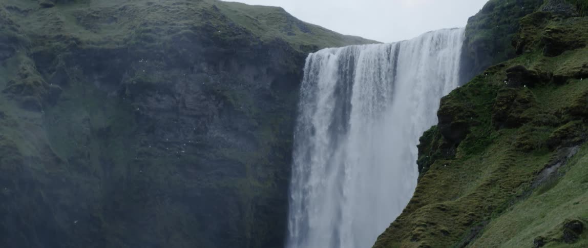 Large waterfall flowing off mountain edge on cloudy day