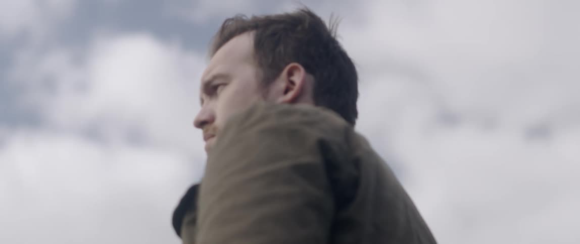 A man stands outside on a cloudy day