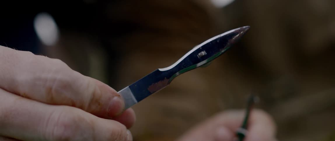 A man plays with a blade in one hand while holding a pen in the other hand