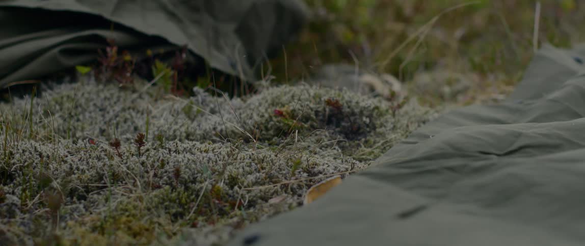 A man uses a rock to hammer in a tent stake