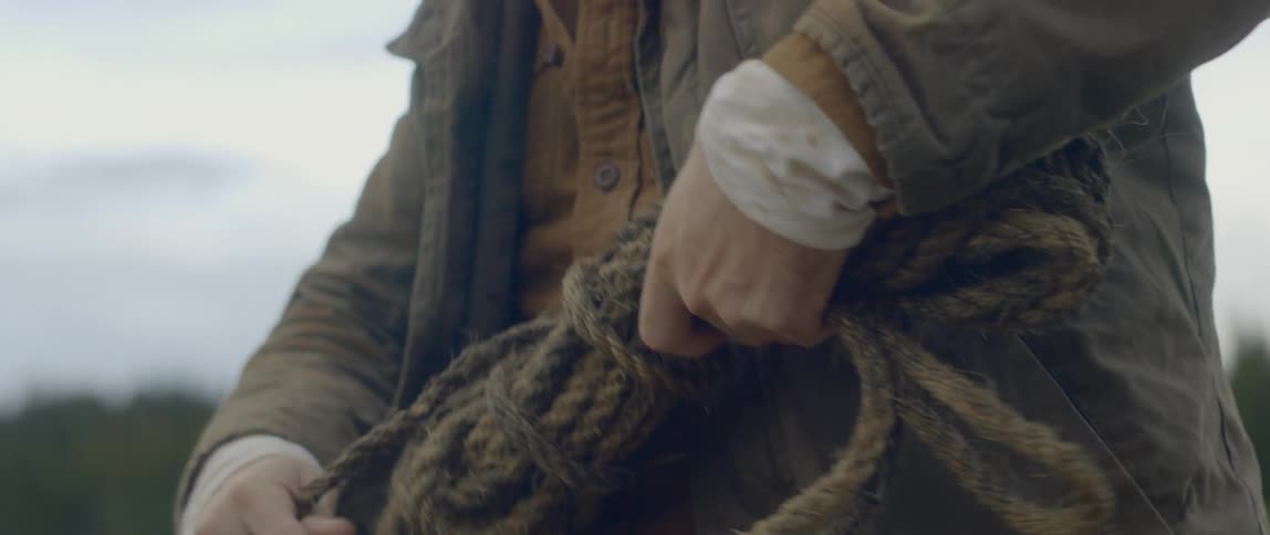 Man unwraps bundle of rope outdoors