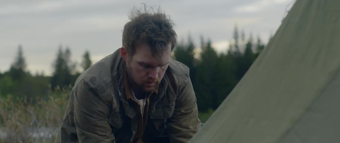 Man building a tent on a grass field at evening