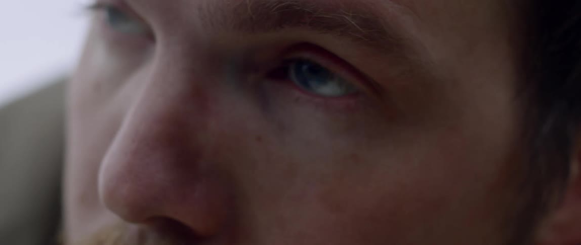 Blonde man looks ahead and blinks during daylight