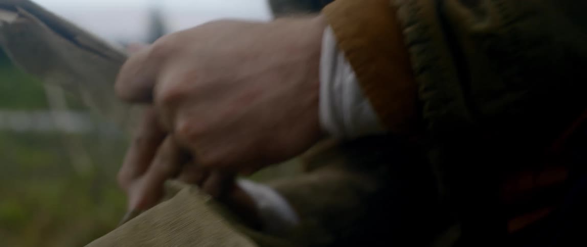 A man outdoors pulls a map out of his bag and searches for something else