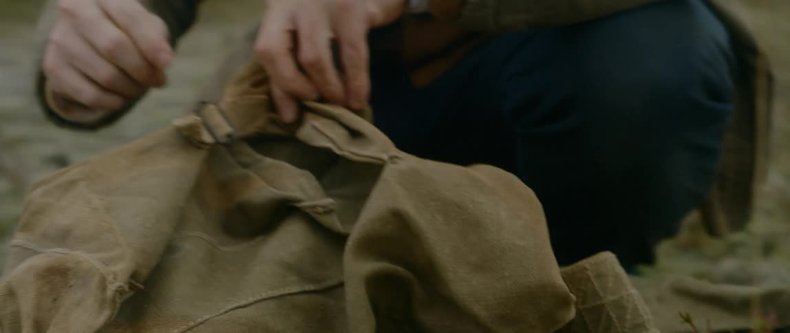 Man inspecting a brown jacket at the middle of no where