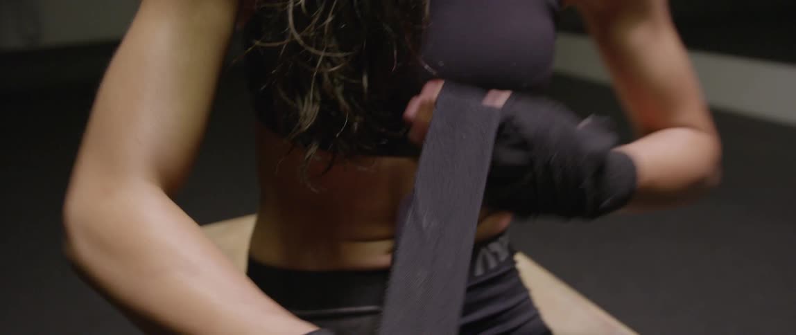 A woman is wrapping her hand with boxing tape