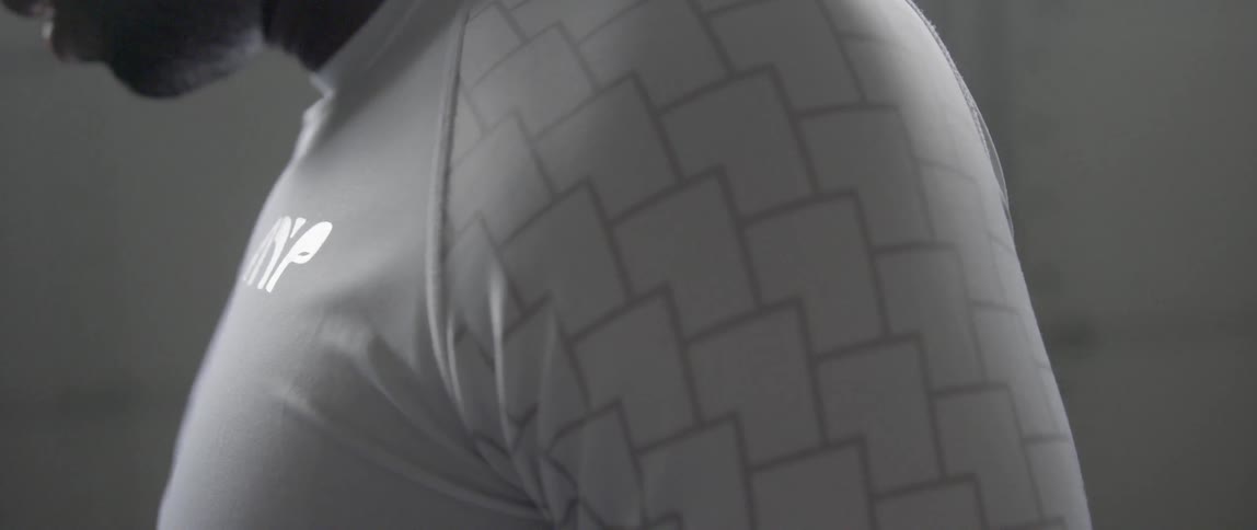 A dark-skinned man is wearing a white athletic shirt