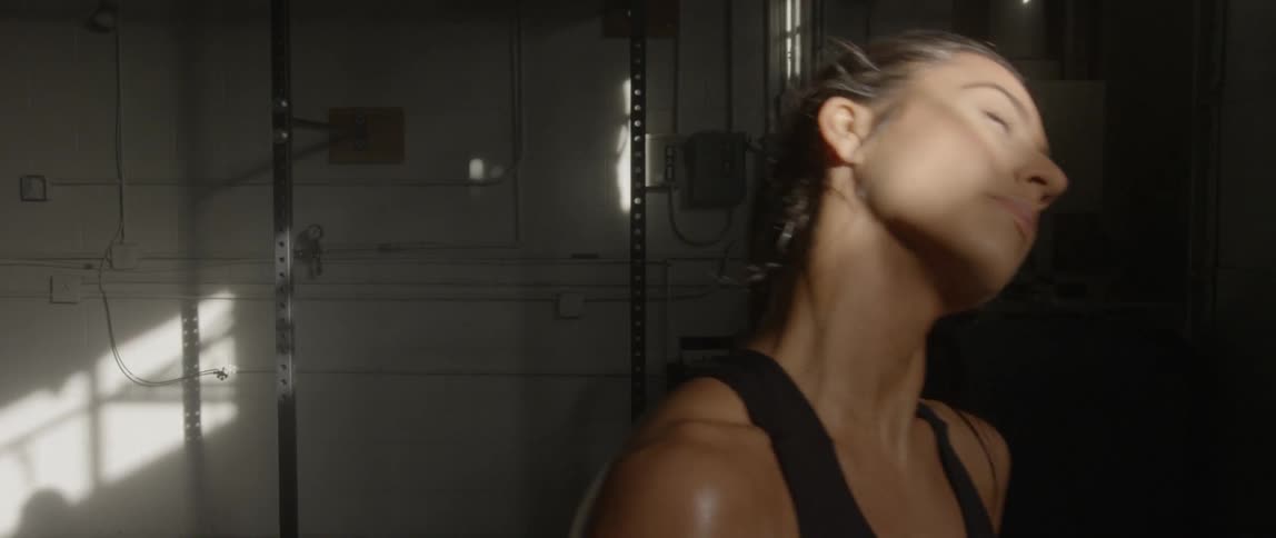 A woman breathes heavily in a gym