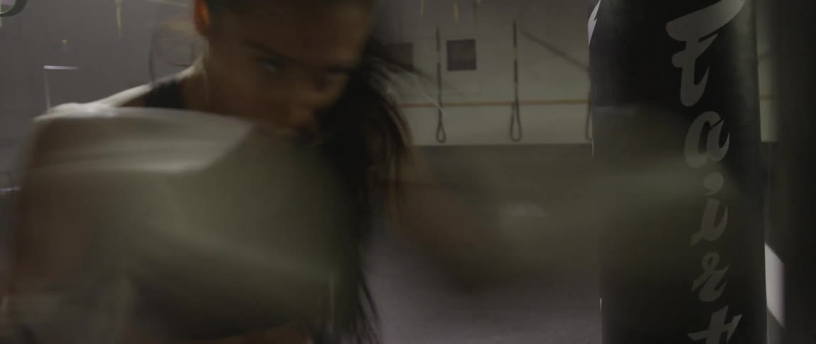 A woman is rapidly punching a bag