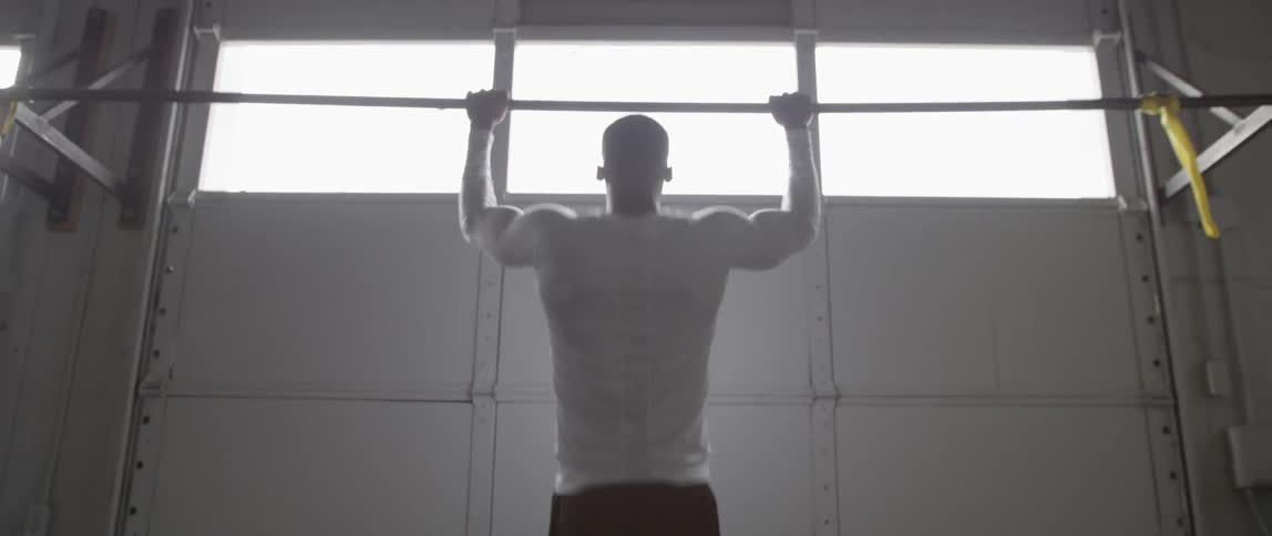 A man is doing pull ups in a garage