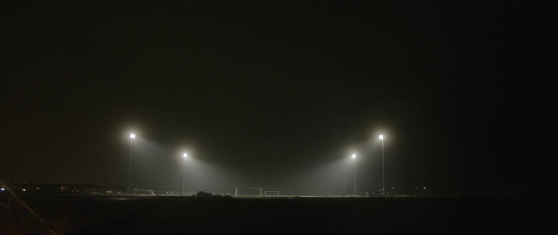 Bright lights shine down on a sports field at night