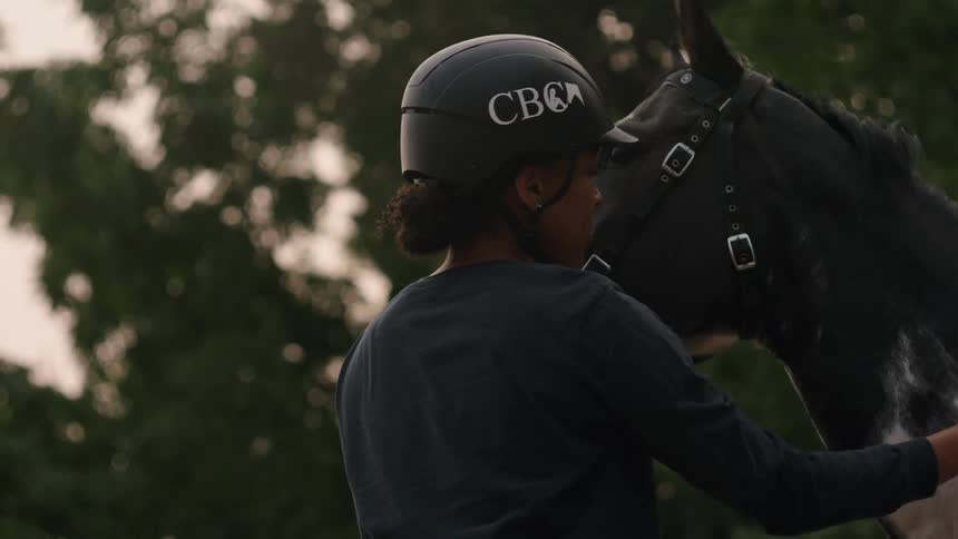 A woman pets and hugs a horse outdoors in the evening