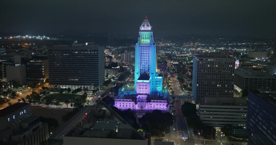 A downtown skyscraper is lit up with pastel lights